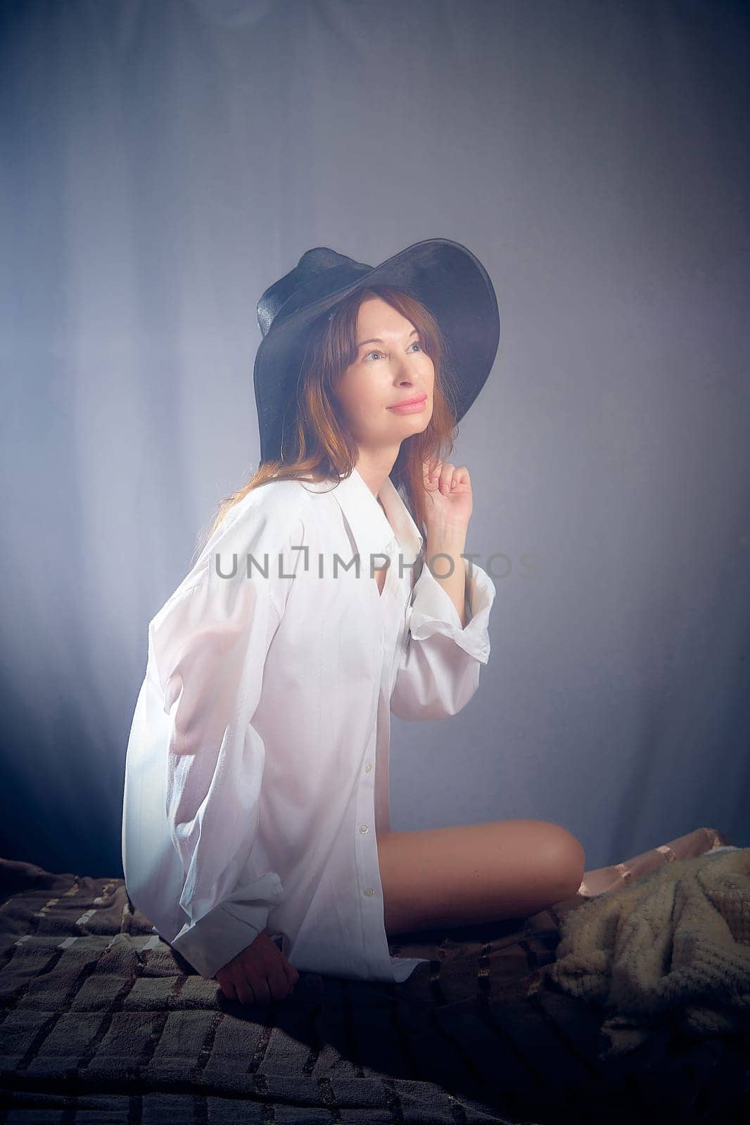 Portrait of a young sexy girl in a white shirt and hat on a grey background. Classic style. dramatic portrait by keleny