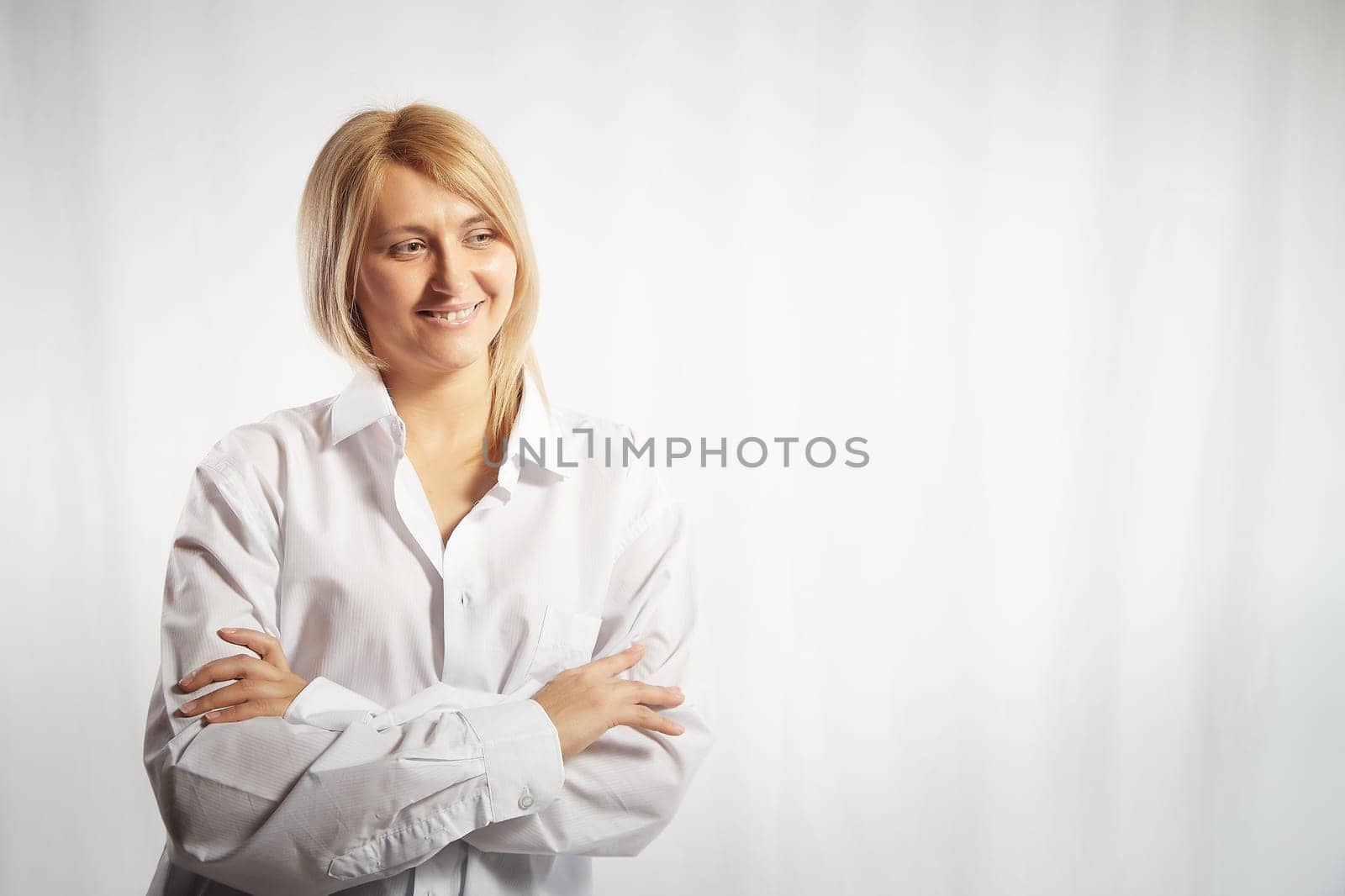 Portrait of a pretty blonde smiling woman posing on white background. Happy girl model in white shirt posing in studio. Copy space