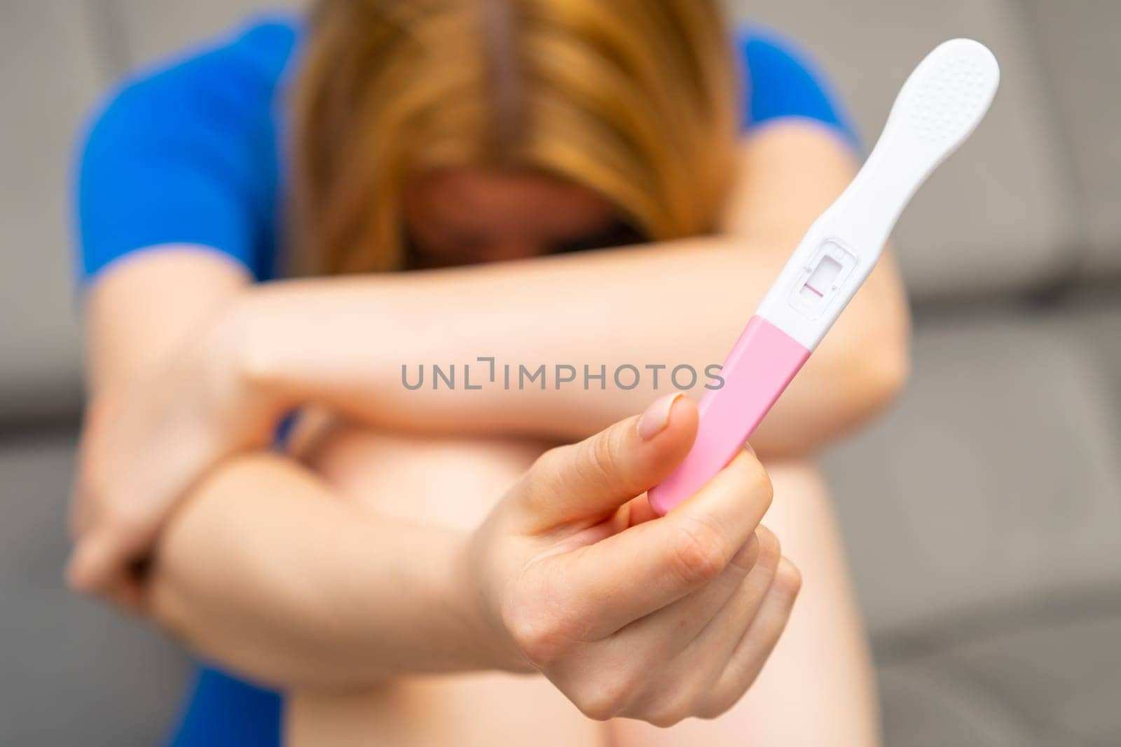 Upset woman holding a negative pregnancy test. Strong wish to have a baby and infertility