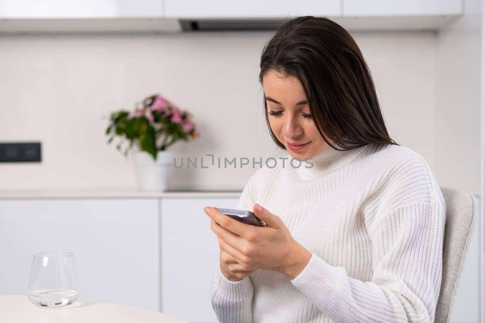 Dreamy millennial girl checking social media holding smartphone in her hands.
