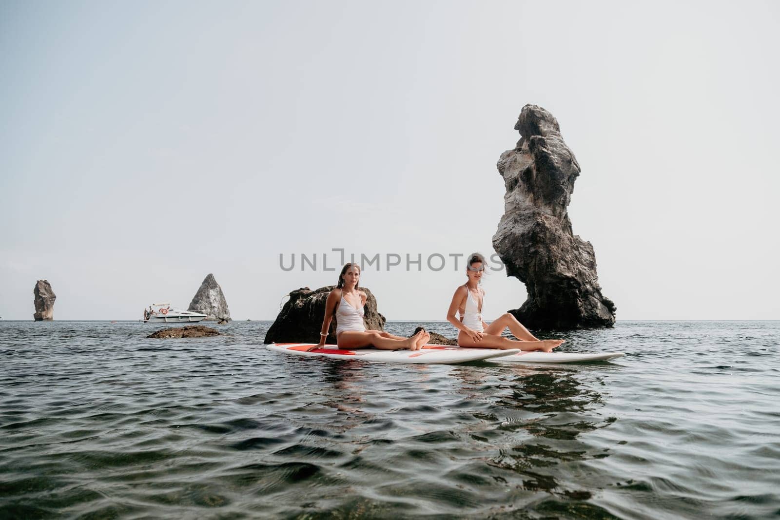 Woman sup yoga. Middle age sporty woman practising yoga pilates on paddle sup surfboard. Female stretching doing workout on sea water. Modern individual hipster outdoor summer sport activity