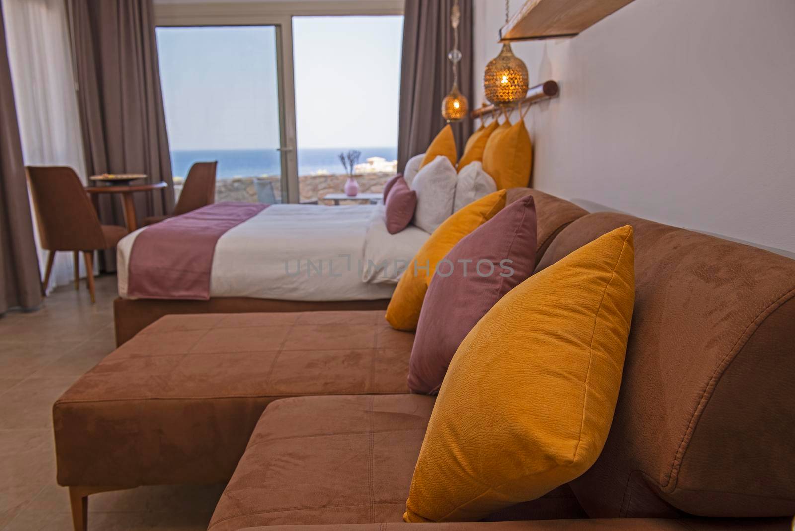 Living room lounge area in luxury studio apartment show home showing interior design decor furnishing with balcony sea view and double bed