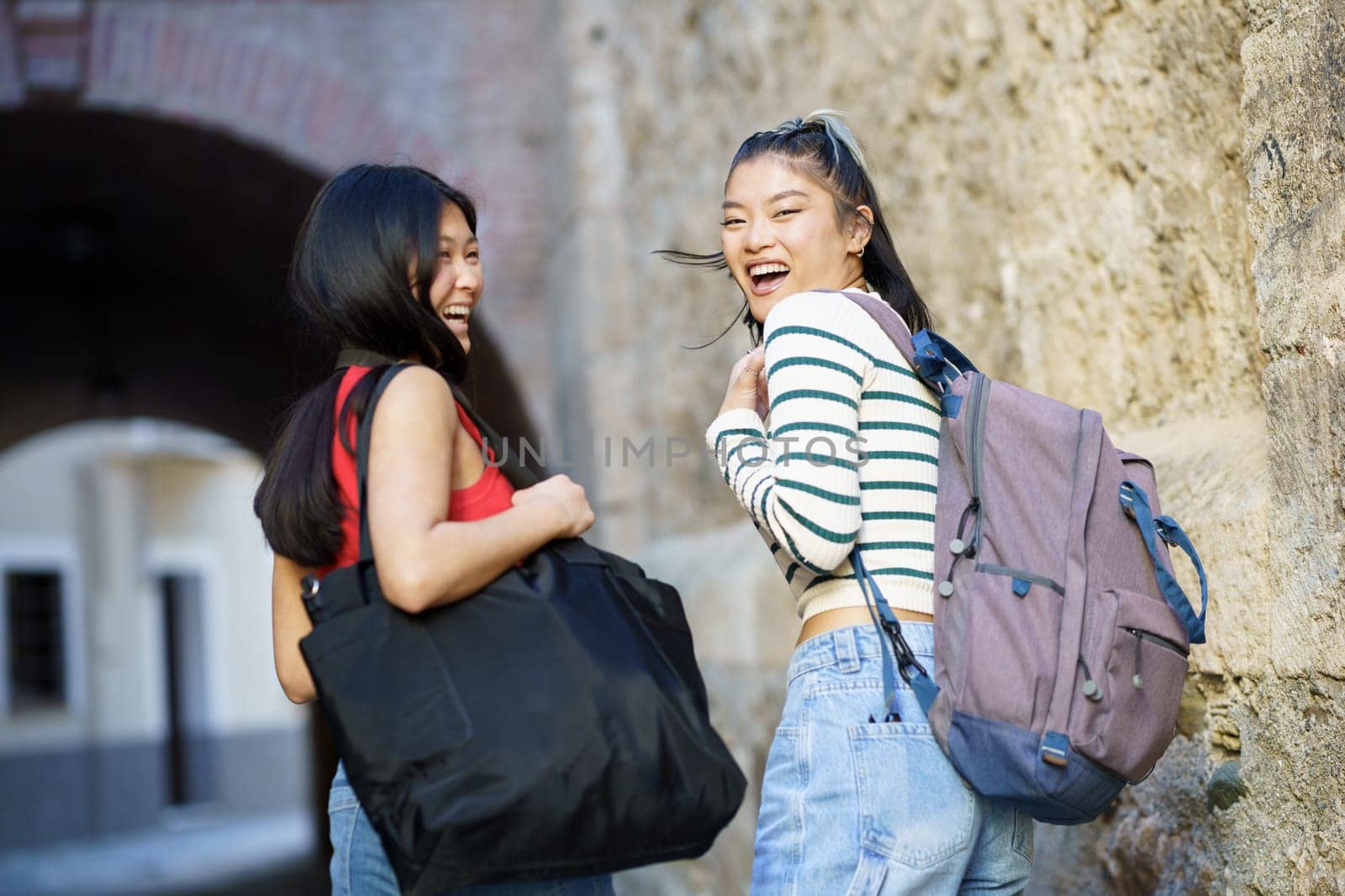 Cheerful Asian women with bags in street by javiindy