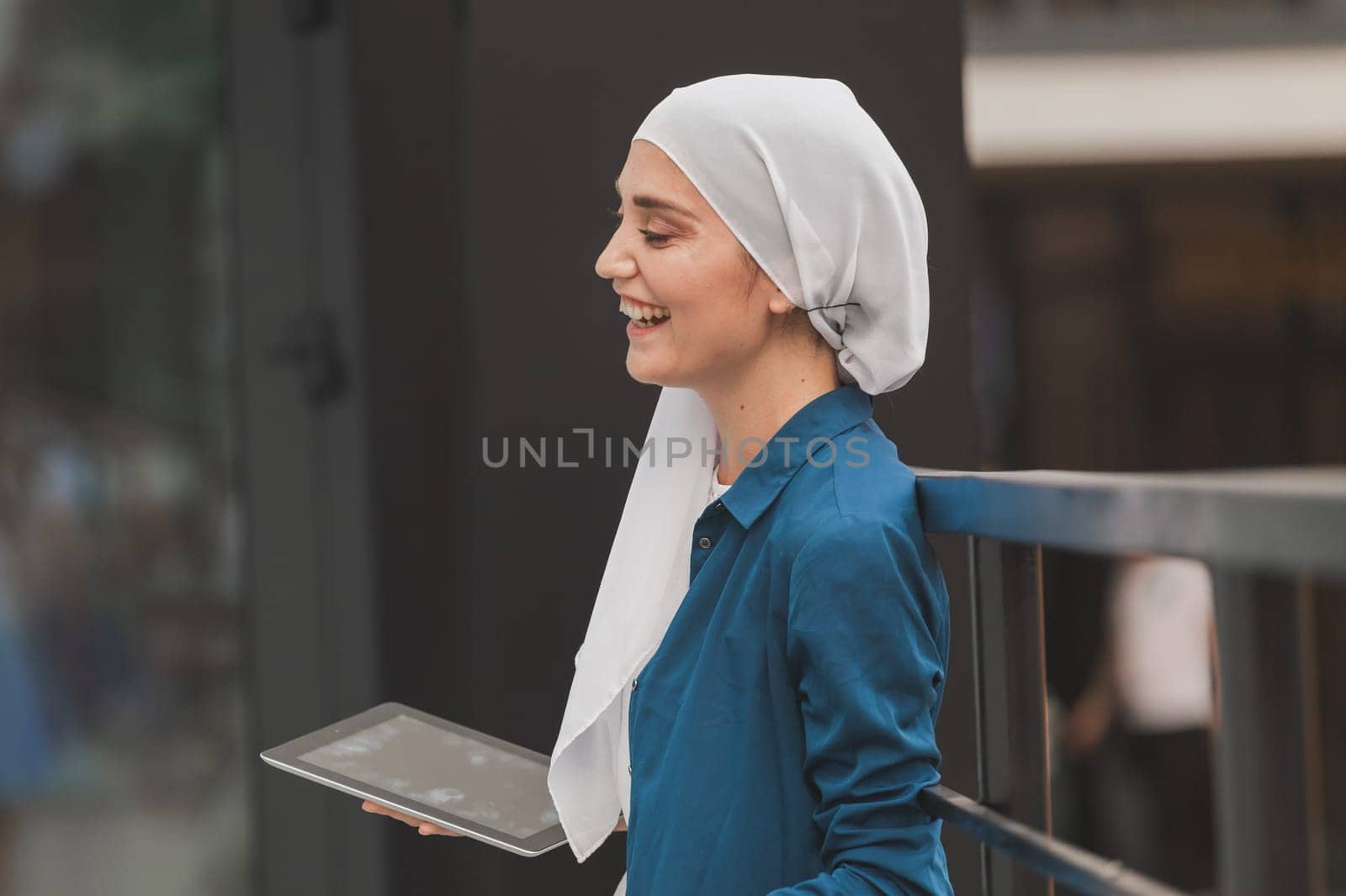 Beautiful muslim girl using digital tablet for communication with friend outdoor.