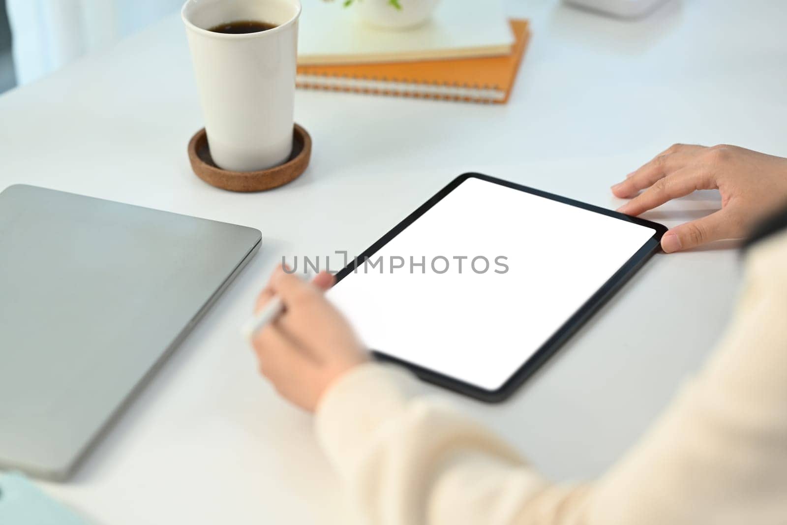 Close up view of young female freelancer working online, browsing internet via digital tablet at working desk.