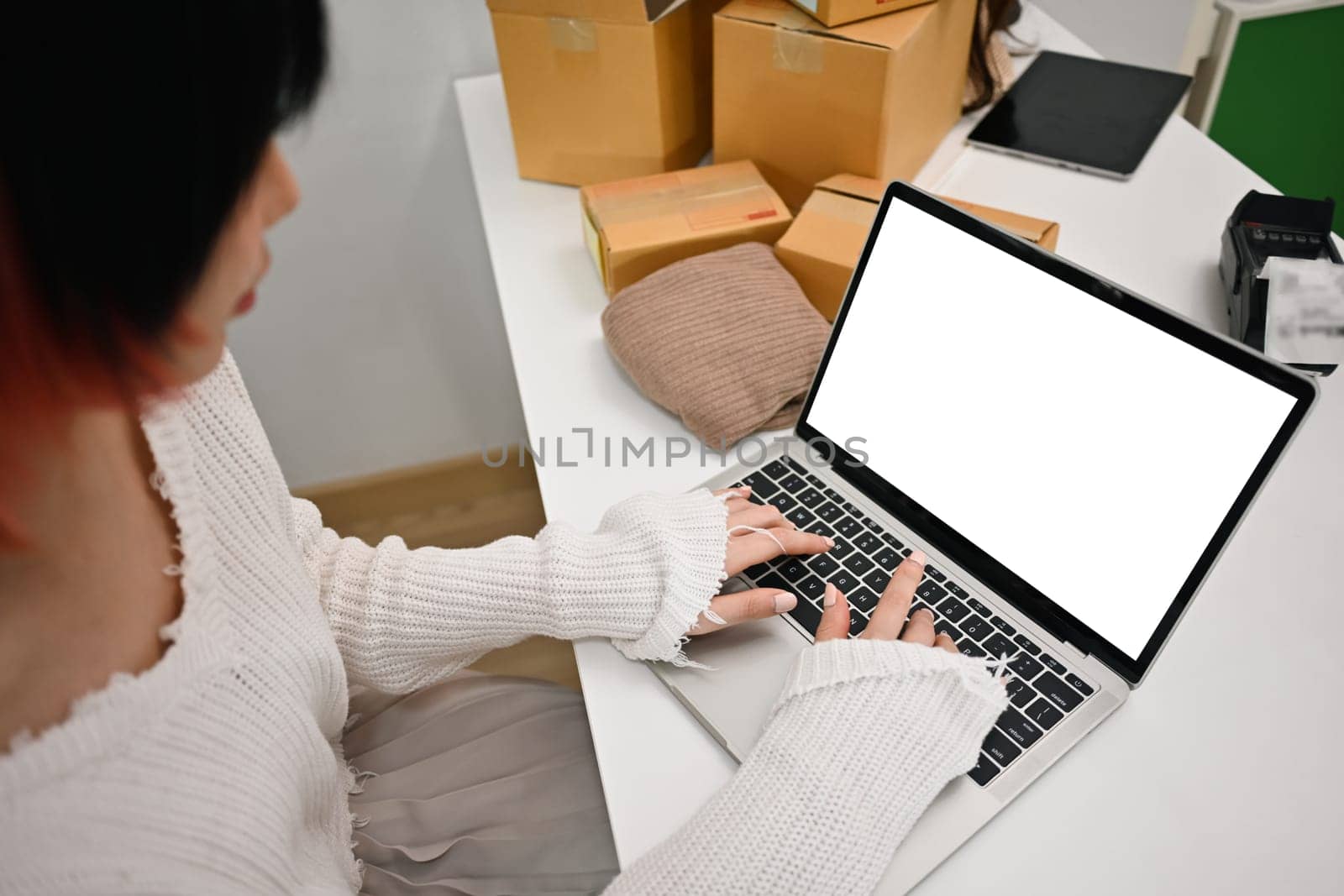 Cropped shot of female online seller using laptop, checking customer address or orders in an online store by prathanchorruangsak