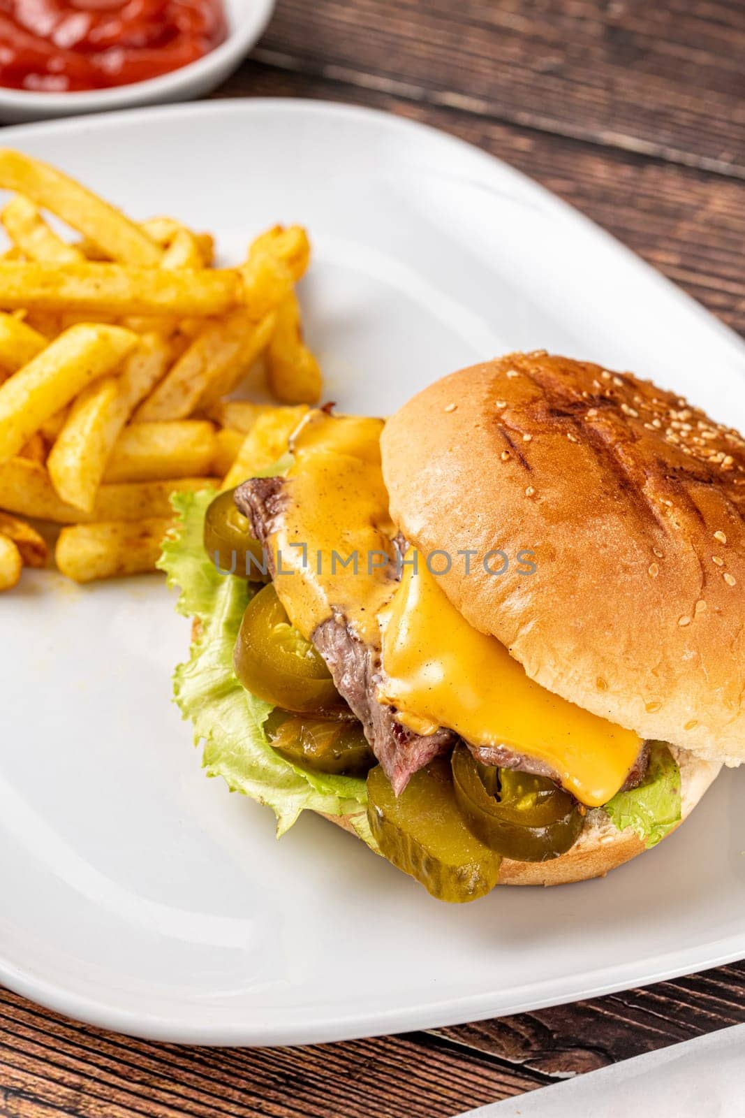 Delicious beef burger with french fries, onion rings and sauces by Sonat