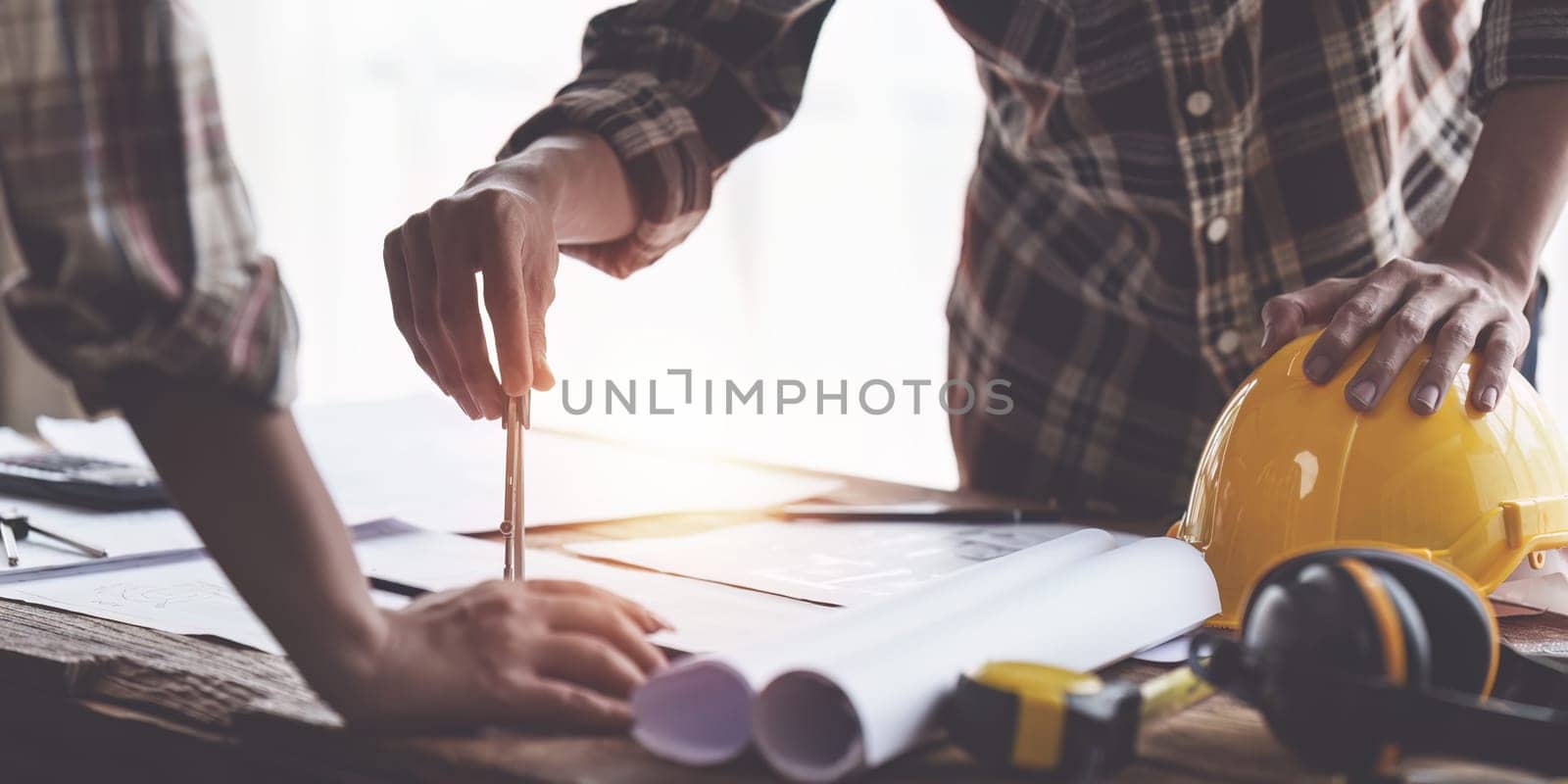 Architect and Engineer working with blueprints for architectural plan, engineer sketching a construction project, green energy concept by itchaznong