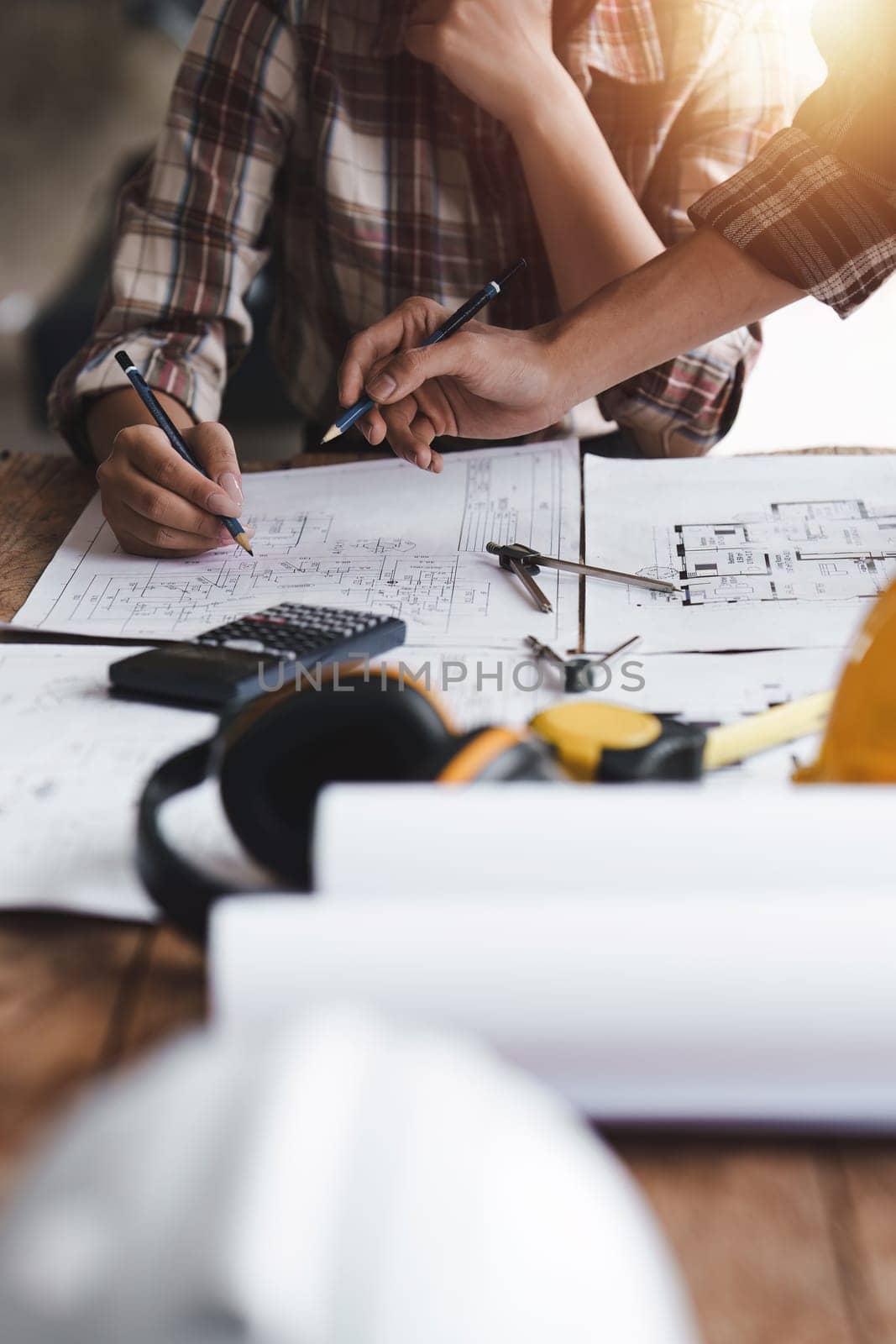 Architect and Engineer working with blueprints for architectural plan, engineer sketching a construction project, green energy concept.