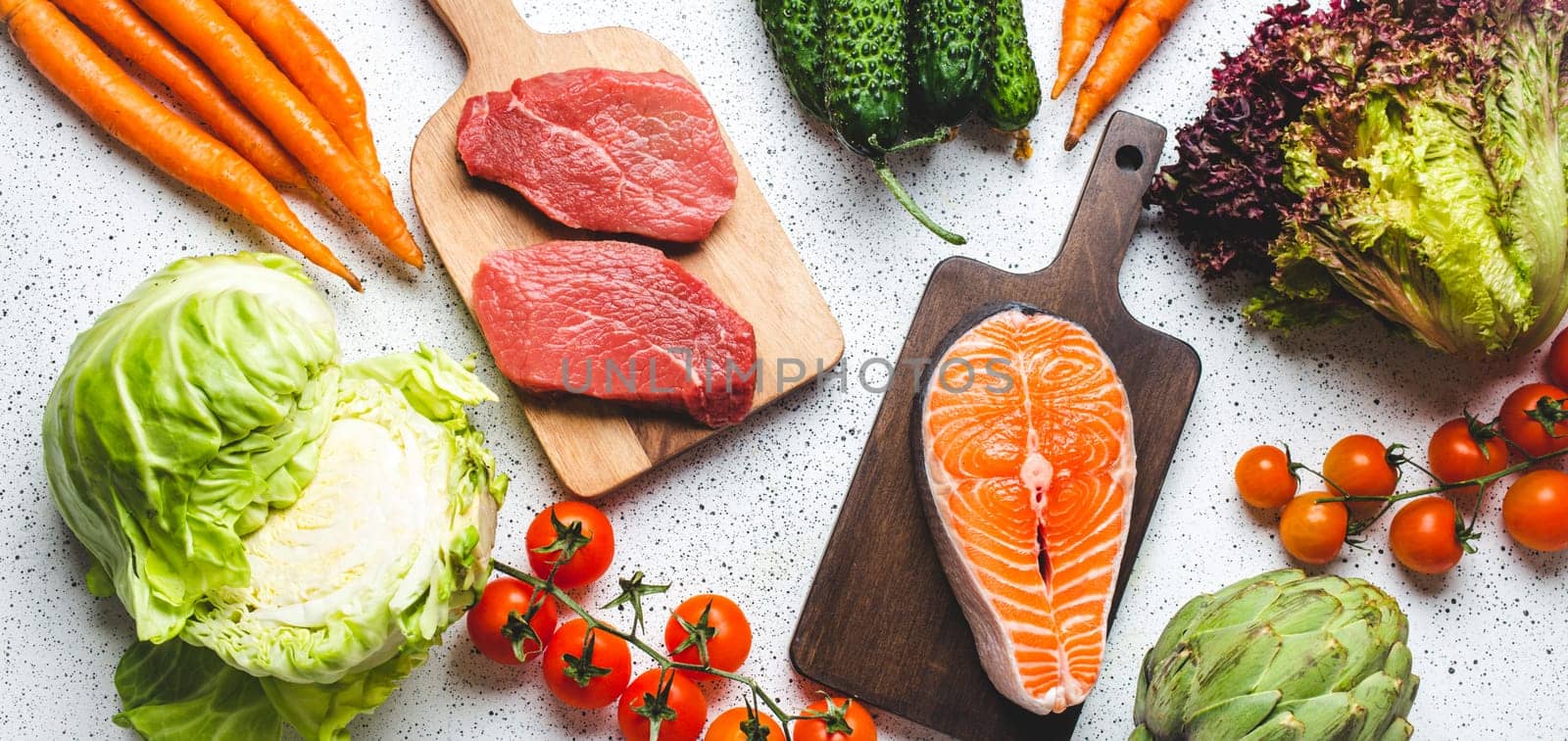 Various food raw products: vegetables, beef meat steak, fish salmon fillet on wooden cutting boards, white rustic table top view. Healthy food ingredients background, diet and balanced nutrition by its_al_dente