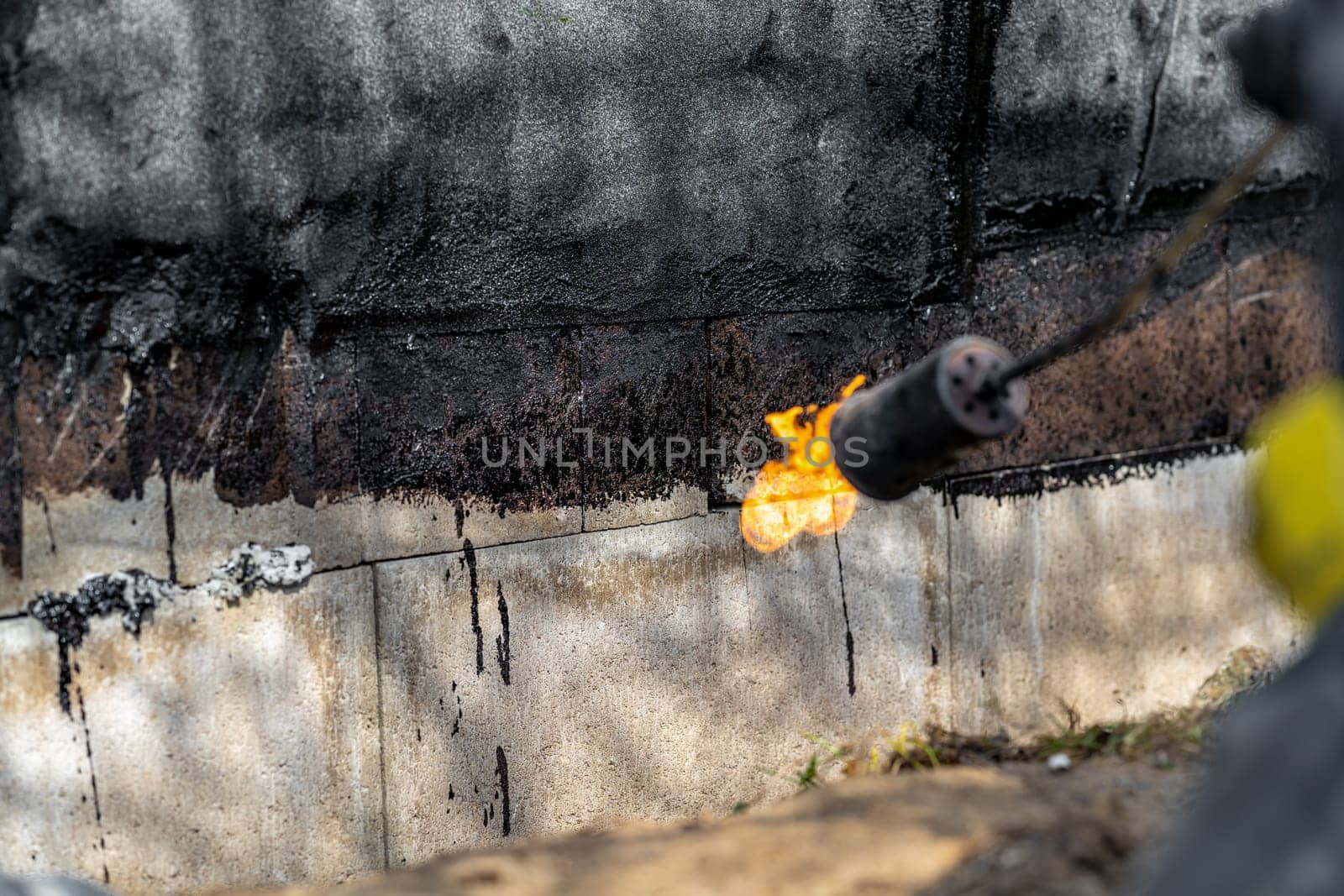 installation of protective waterproofing on the foundation and walls of the building. warmed by an open fire by Edophoto