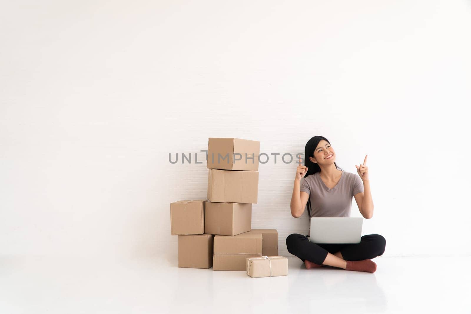 Happy Asian young entrepreneur, Smile for sales success and pointing finger up at the home office and store, Concept of merchant  business online, eCommerce and delivery and lifestyle by PattyPhoto