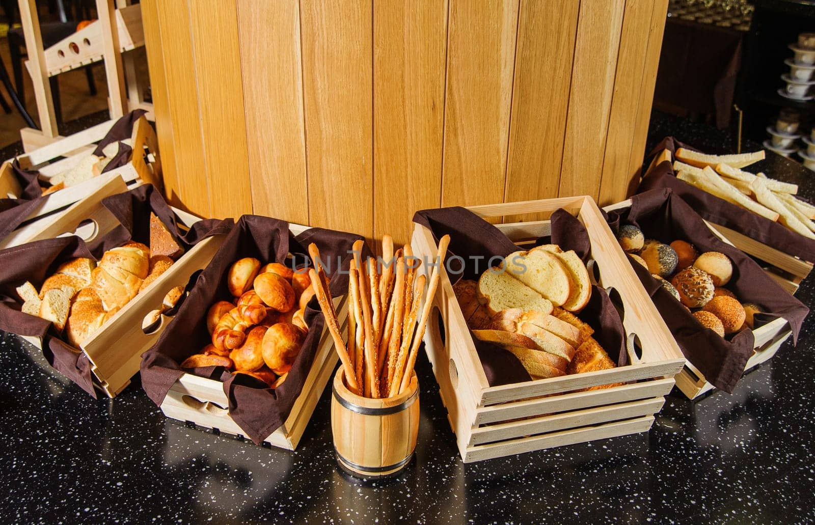 A buffet table with variety of bread in the wooden baskets