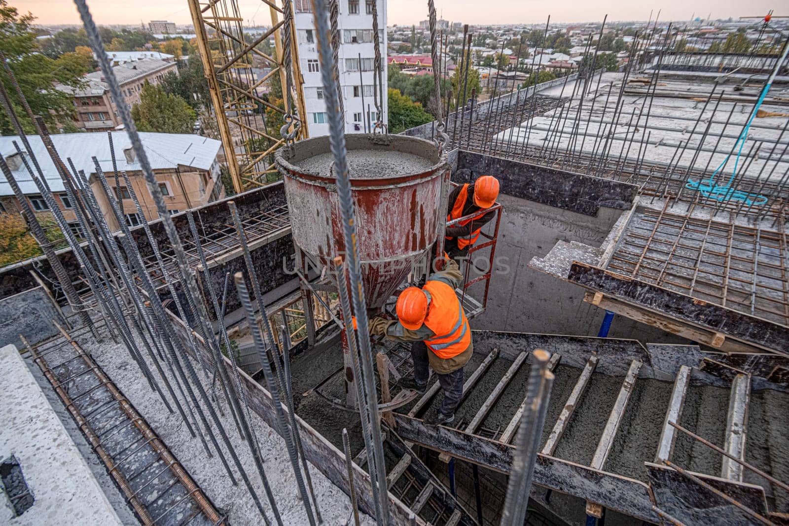 The workers on a building infrastructure roof with machinery and tools. Pouring concrete into a mold by A_Karim