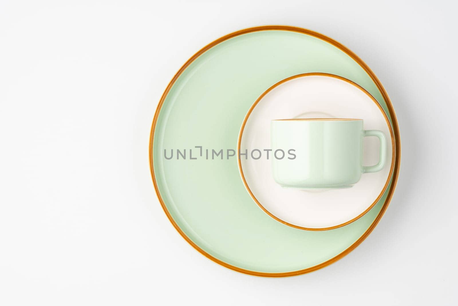 A set of white and pastel green ceramic tableware with orange outlines