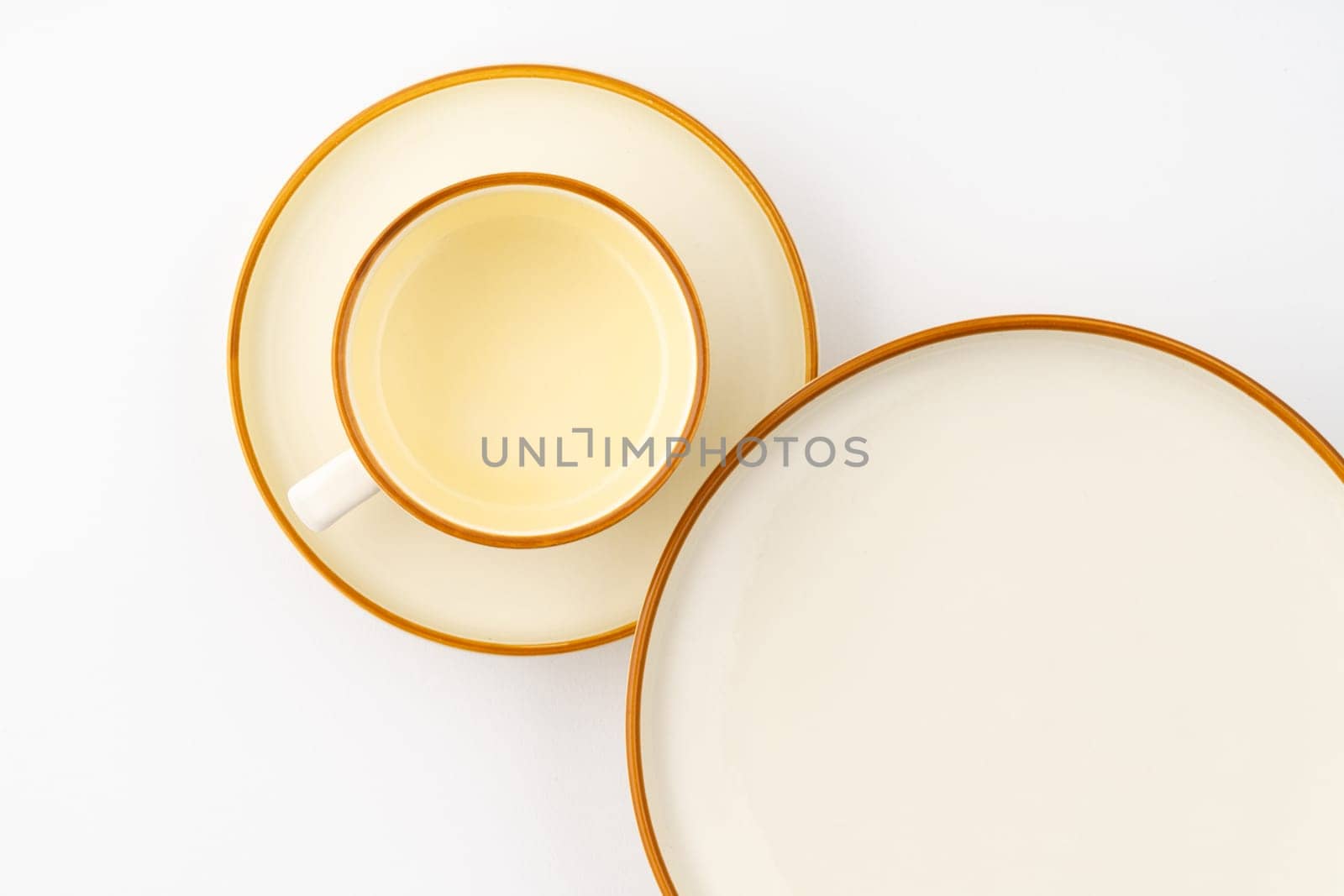 A set of white and brown ceramic plate and cup on a white background. Top view