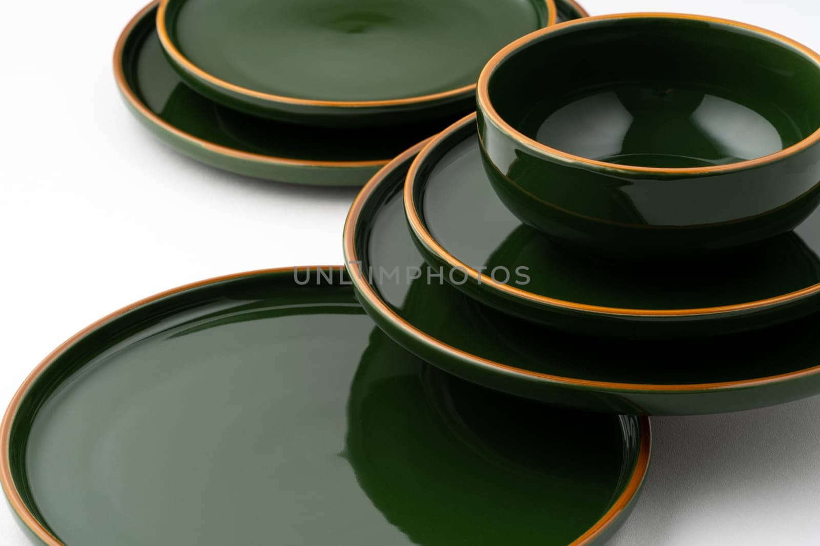 A set of green ceramic plates and bowl on a white background