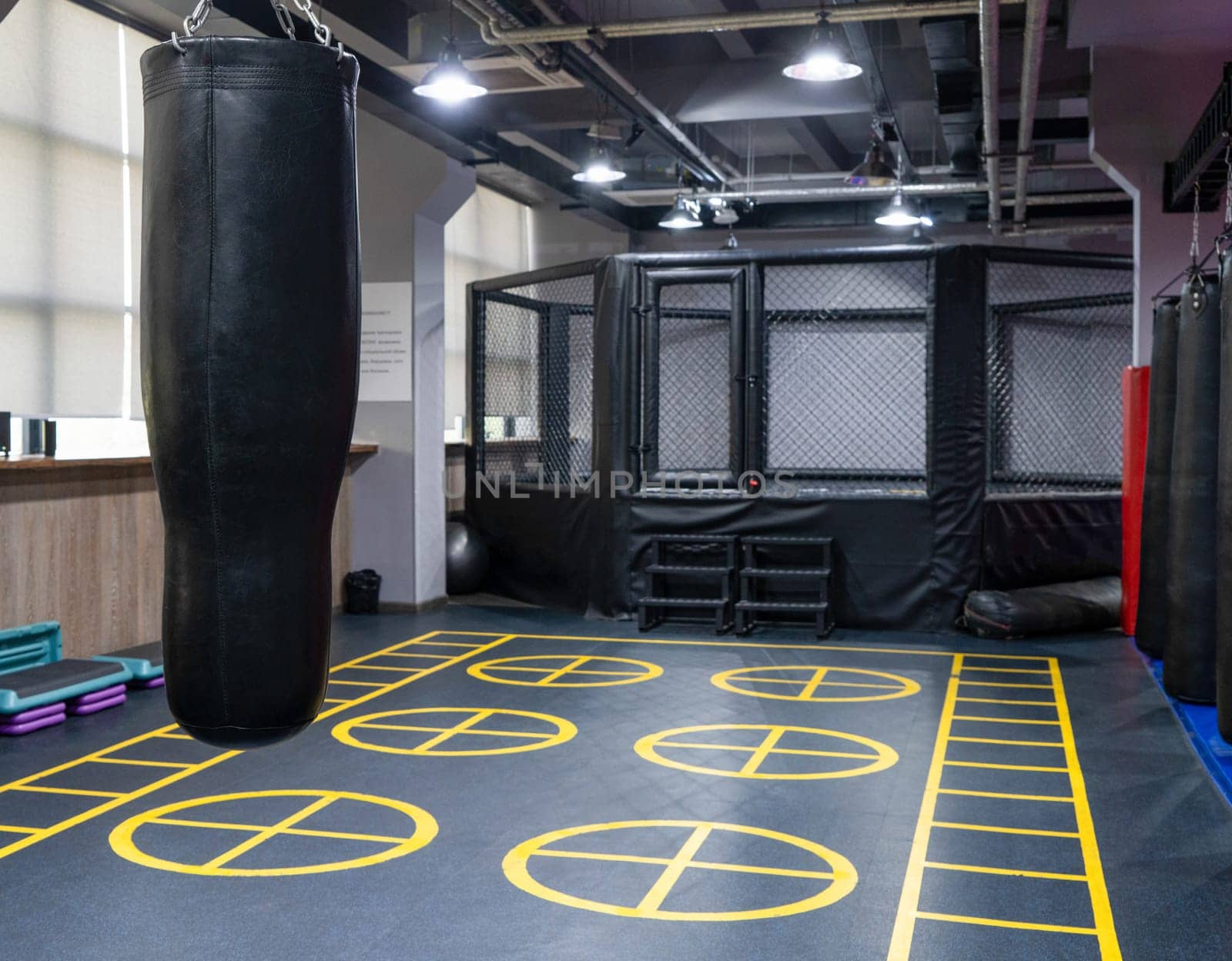 An octagonal kickboxing cage with boxing bags in the sports complex