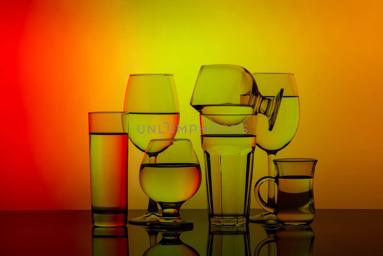 Some glasses for different drinks stacked on a colorful background