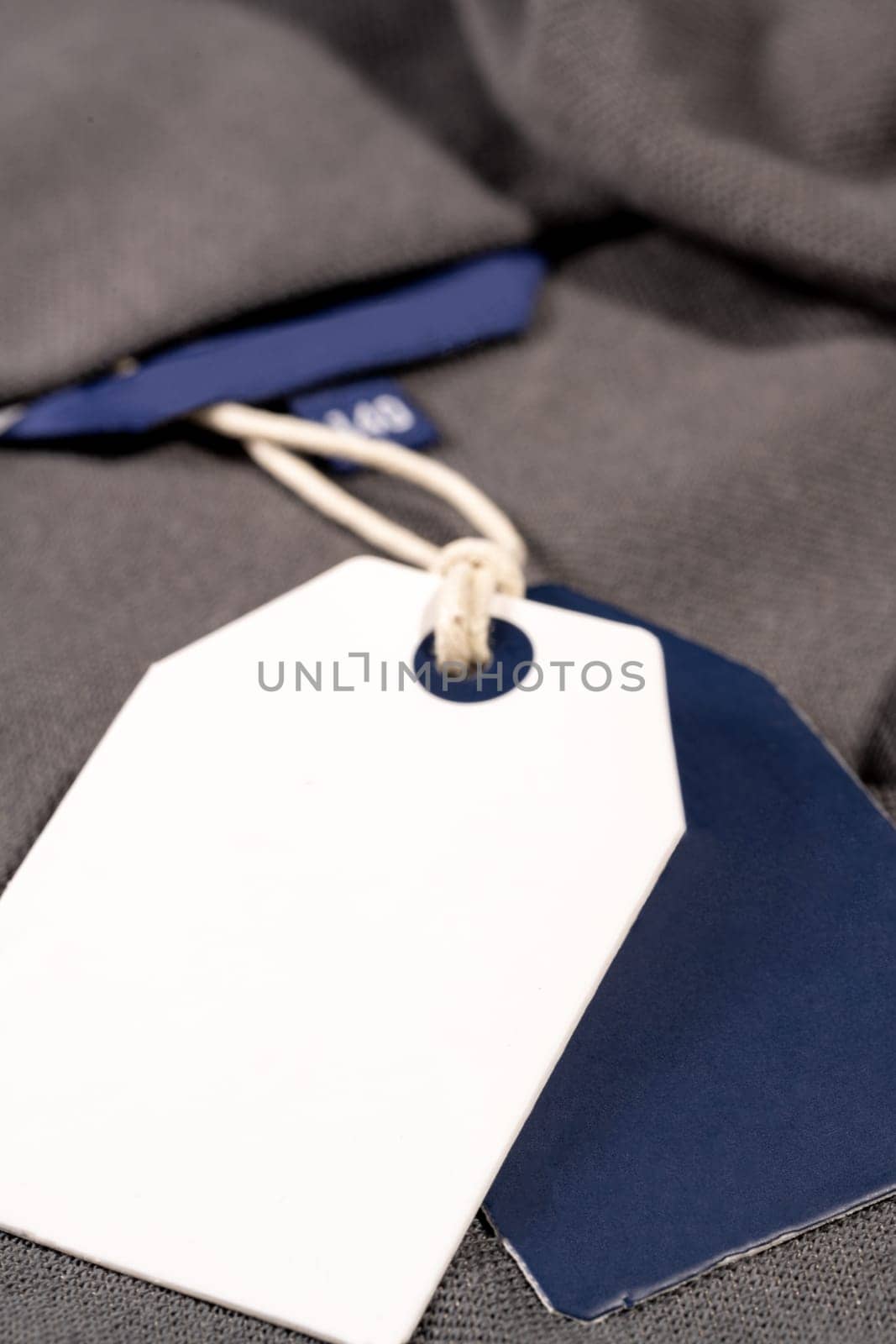 A vertical closeup shot of white blue tags on a string on a cloth with a blank blue tag on the neck