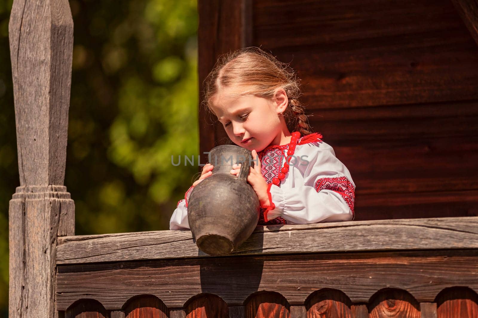 Girl in Ukrainian national dress with a jug outdoors