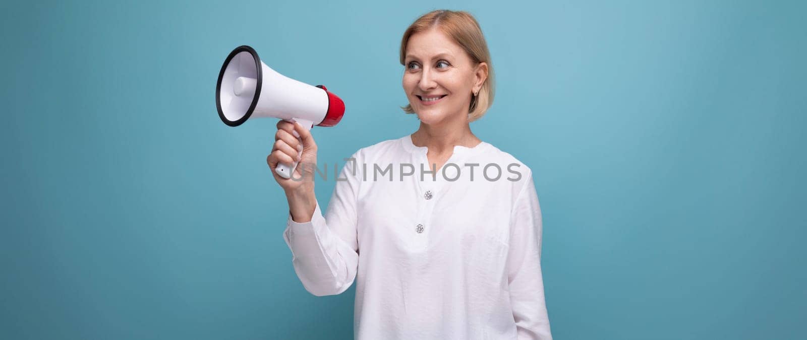 mature woman with blond hairstyle speaks important news with loudspeaker.