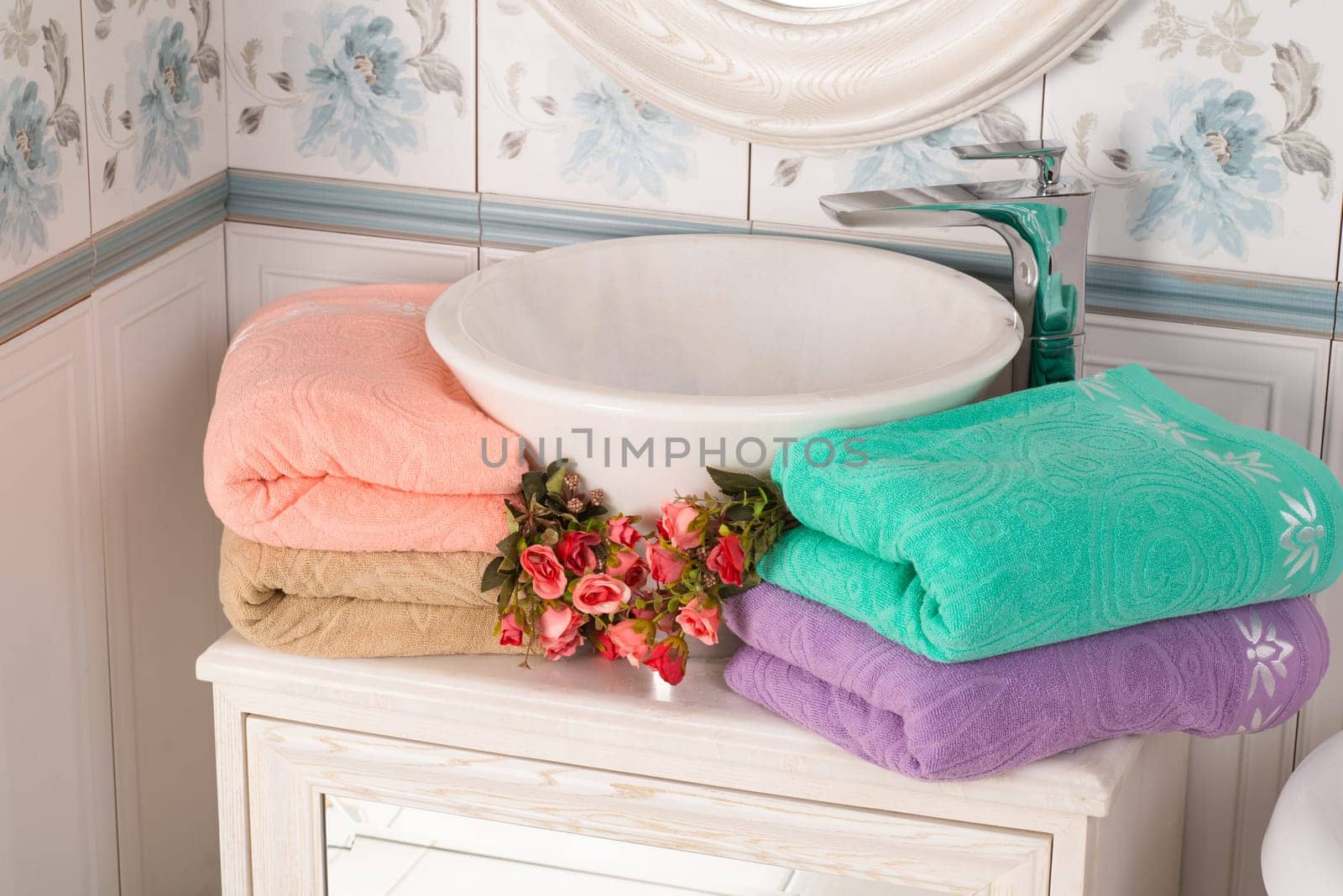 The beautiful folded pink, turquoise, and purple bamboo towels near a bathroom sink by A_Karim