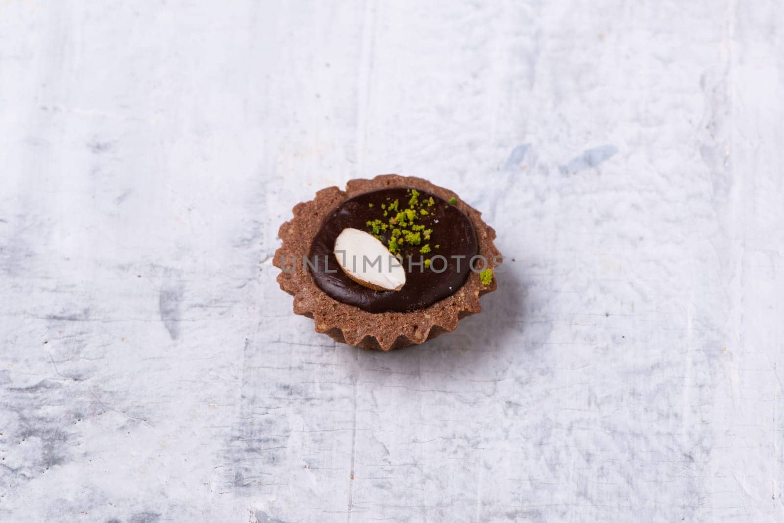 A closeup shot of a Mini Chocolate Hazelnut Tart on a white marble surface by A_Karim