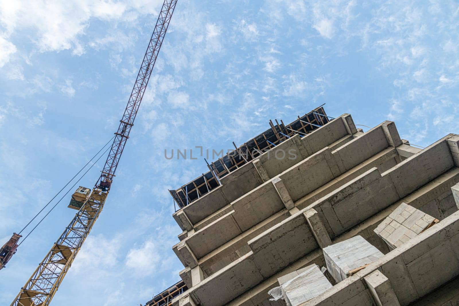 A low angle shot of a crane with equipment on a construction site near a new building infrastructure