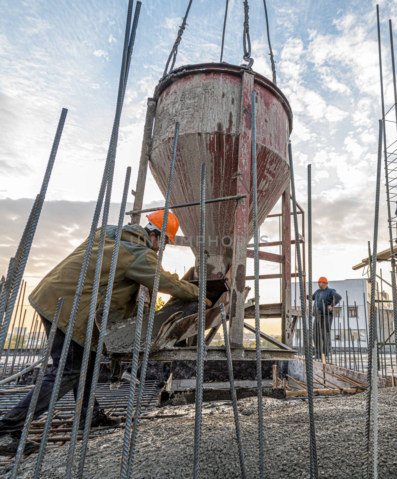 The workers on a building infrastructure roof with machinery and tools. Pouring concrete into a mold by A_Karim