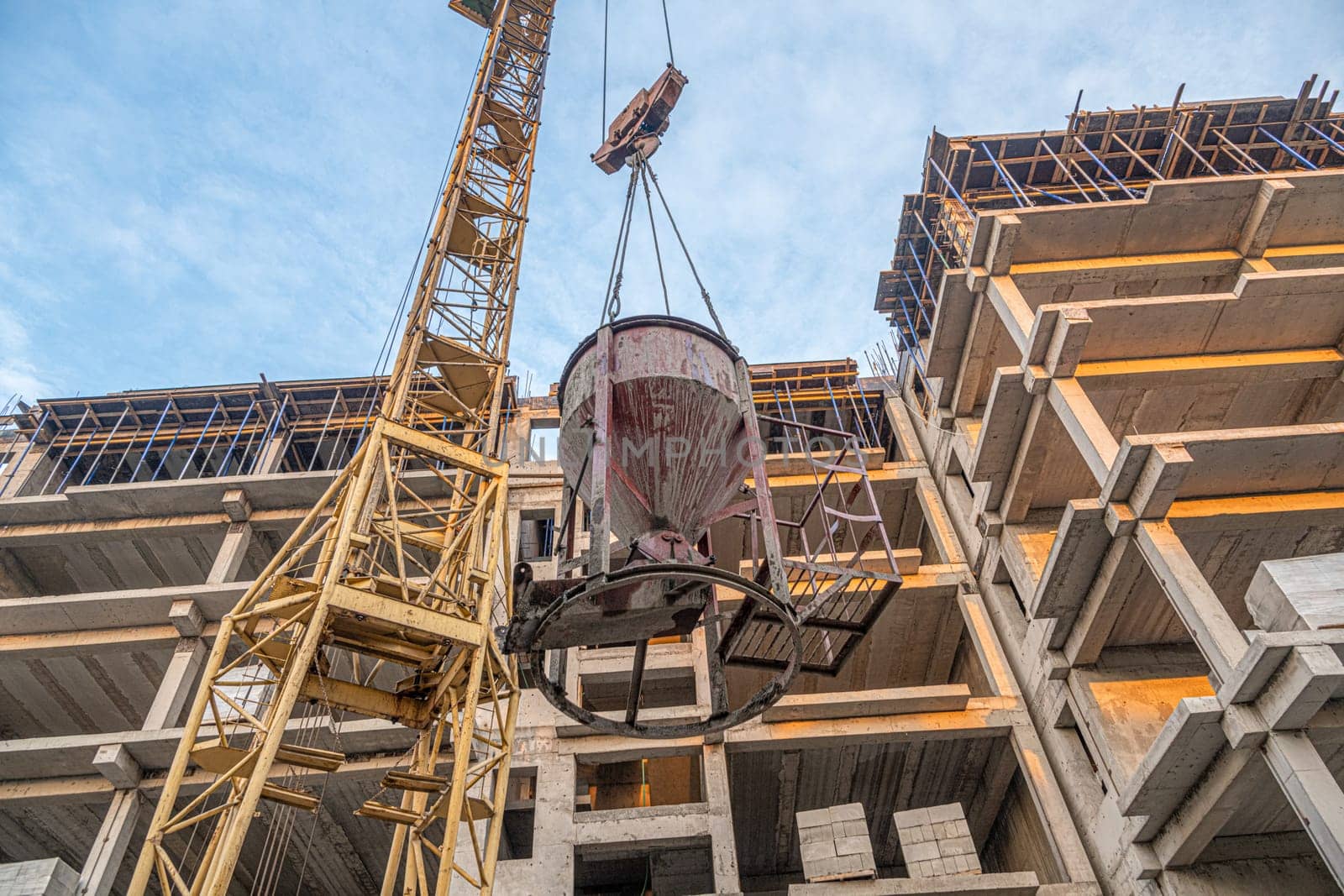 A low angle shot of a crane with equipment on a construction site with a new building infrastructure. Pouring concrete into a mold by A_Karim