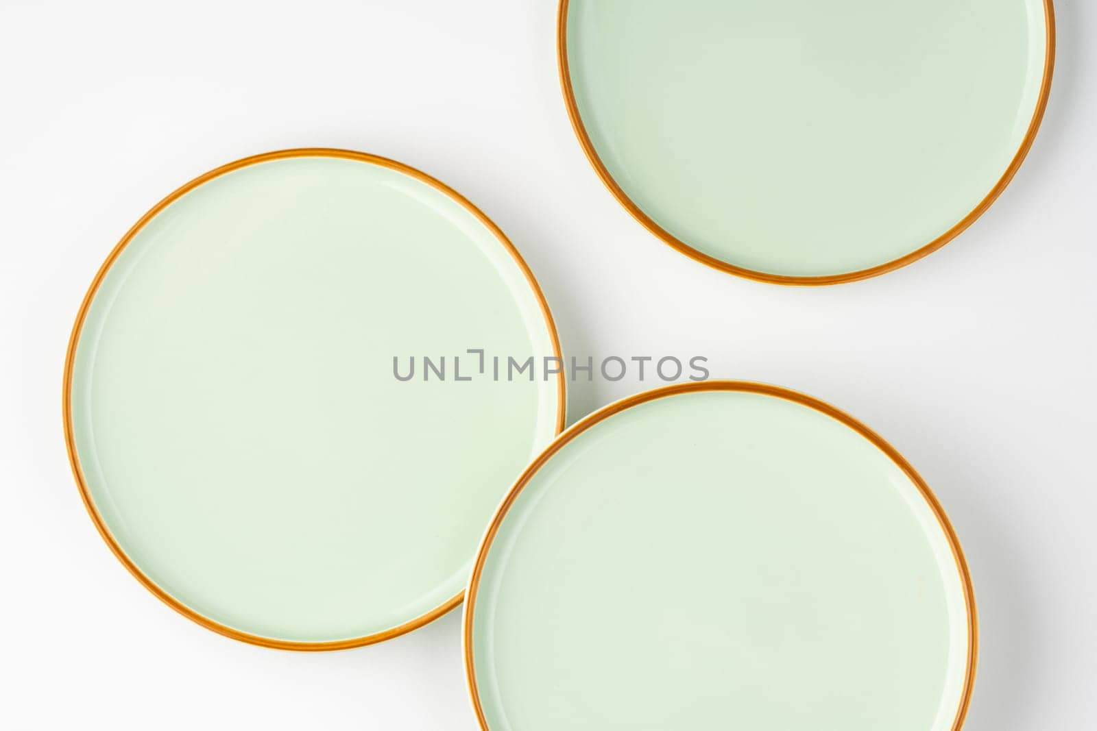 A set of pastel green ceramic tableware with orange outlines. Top view by A_Karim