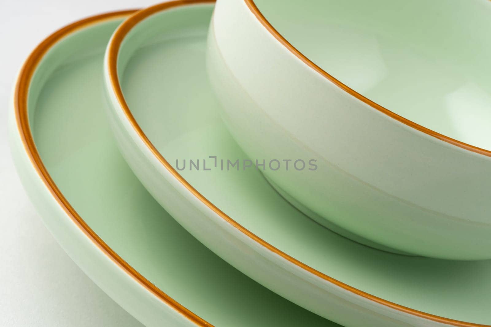 A set of pastel green ceramic tableware with orange outlines. Close-up