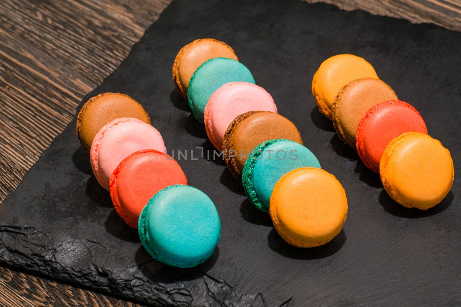 The multicolored French macaroon cookies on a black stone