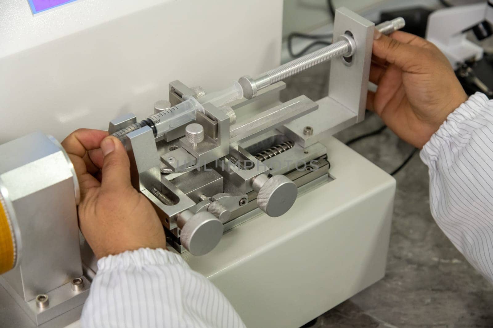 A closeup shot of hands working on a machine in a medical production warehouse for syringes