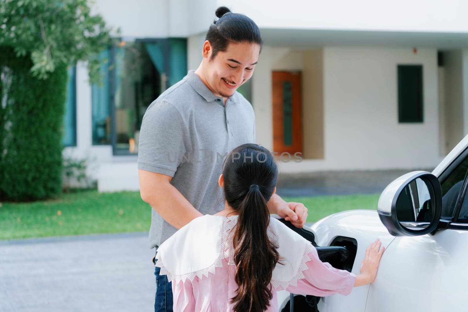 Progressive concept of father and daughter with EV car and home charging station by biancoblue