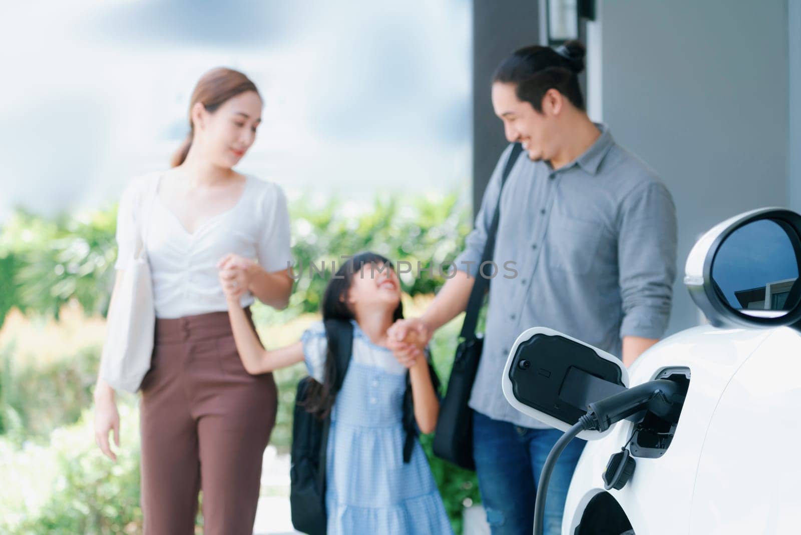 Focus home charging station for EV car, blur progressive family in background. by biancoblue