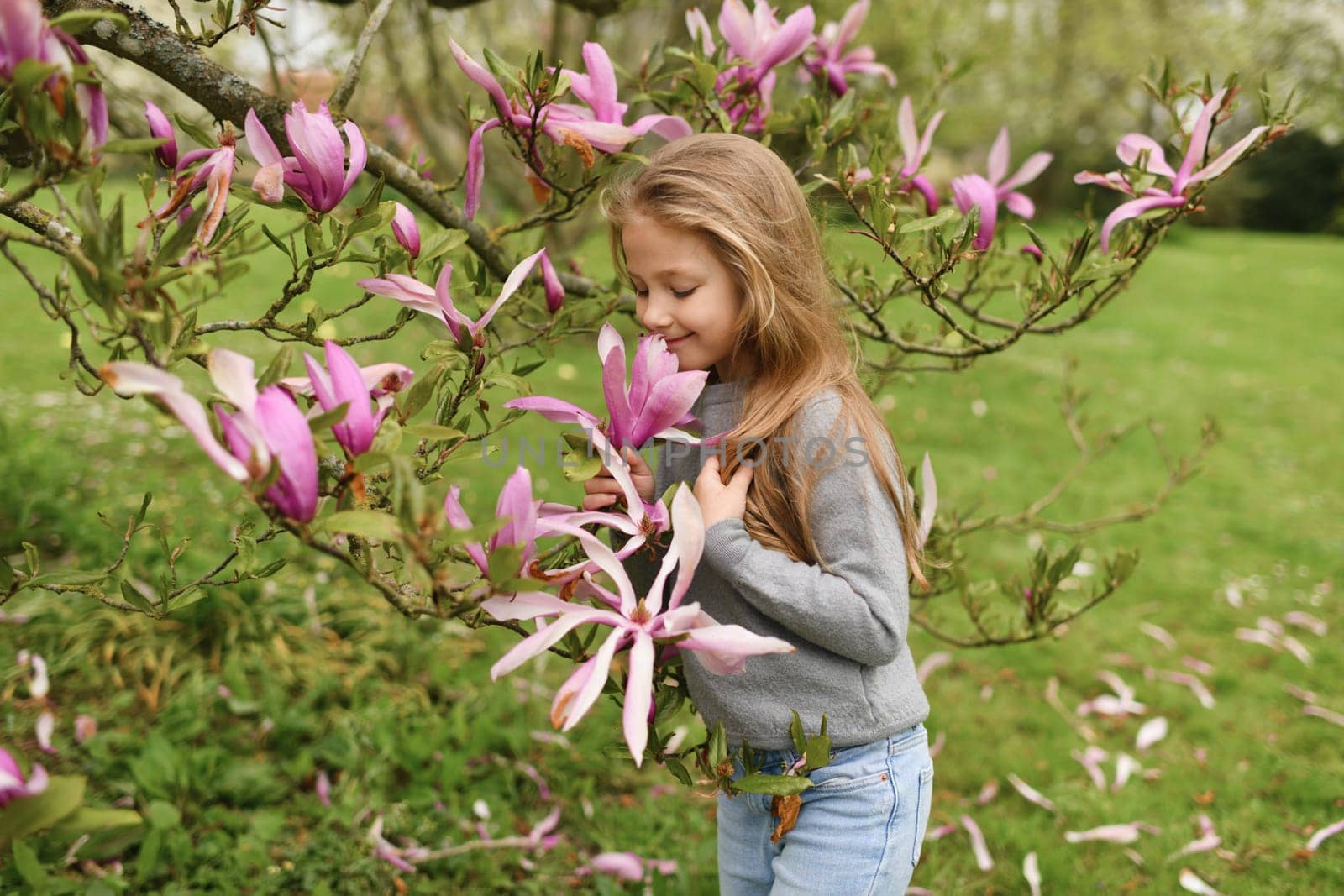 A little girl smelling pink magnolia