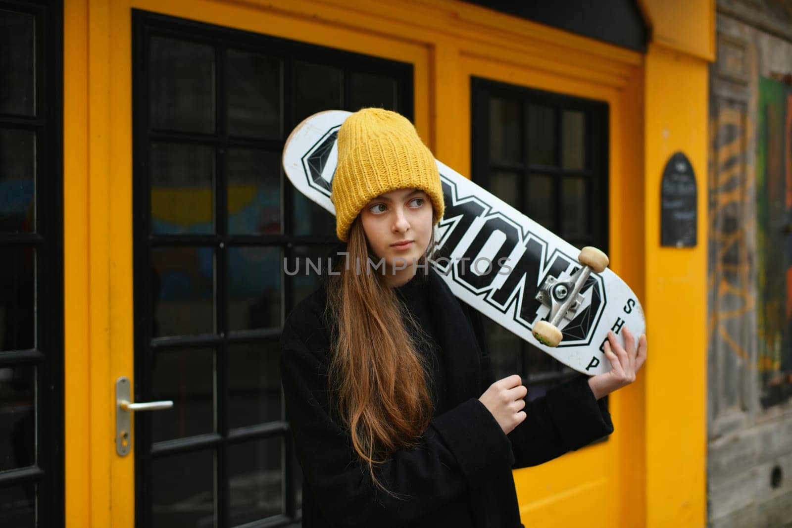 A girl in a yellow hat with a skateboard