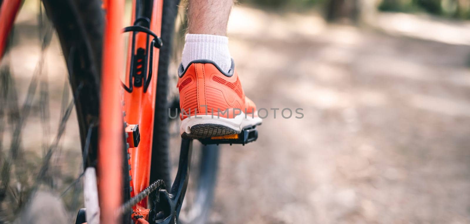 Leg in sneaker on bicycle pedal during riding outdoors