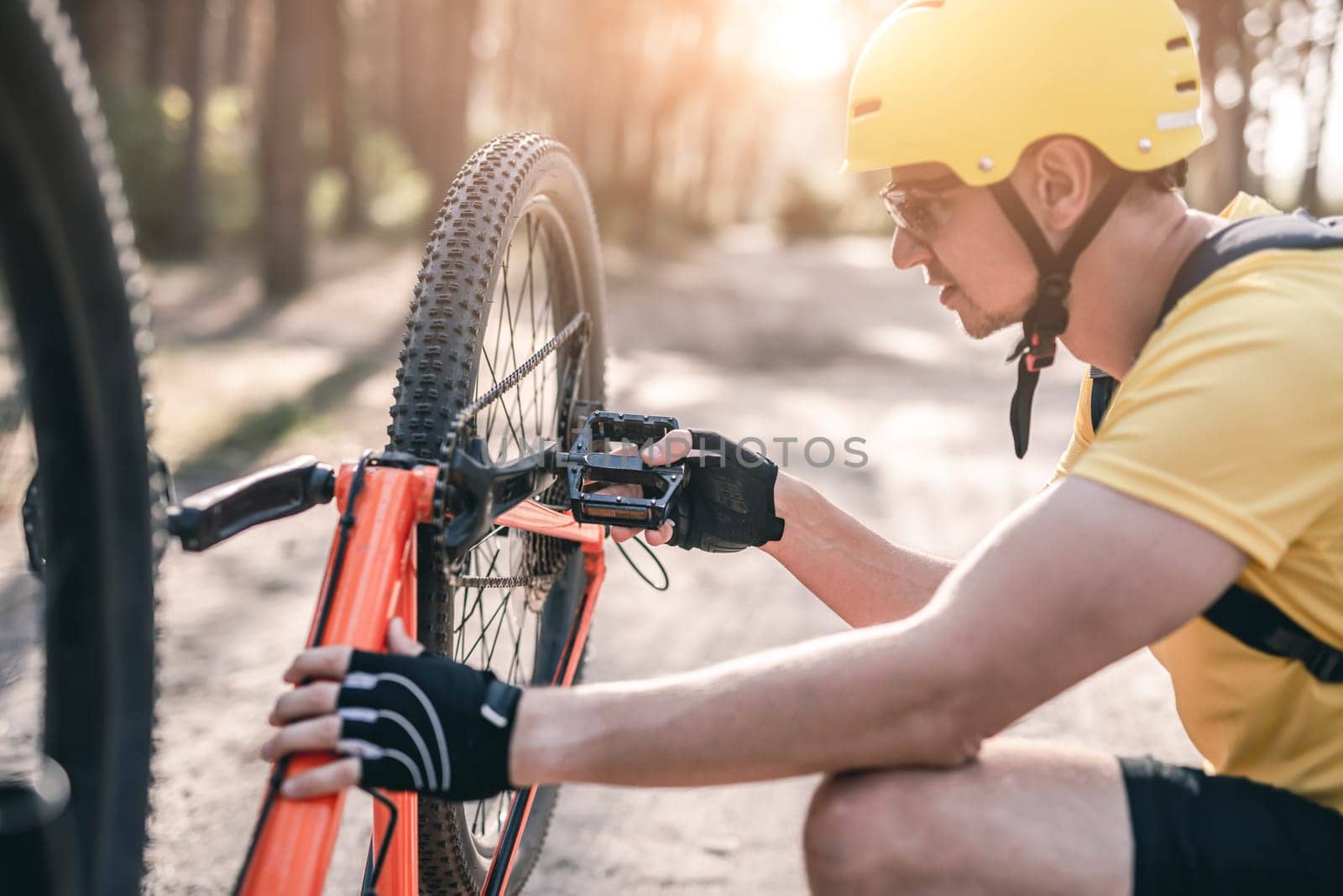 Man checking chain mechanism on bike while riding in forest