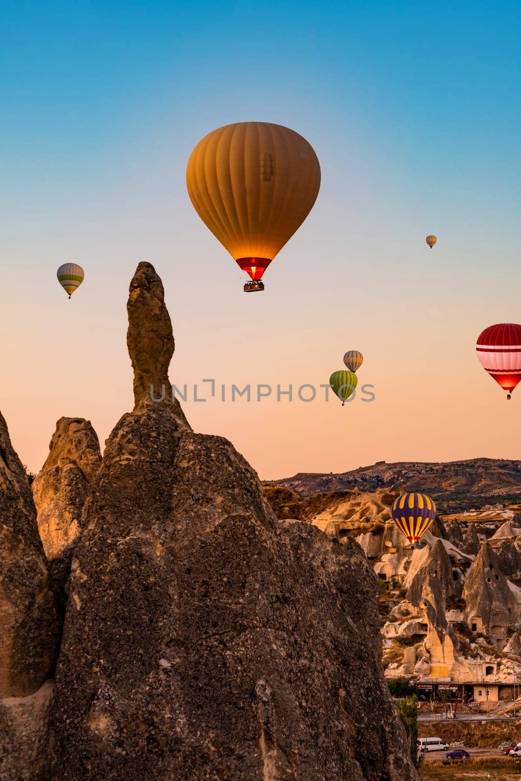 Lots of hot air balloons floating in sunset sky