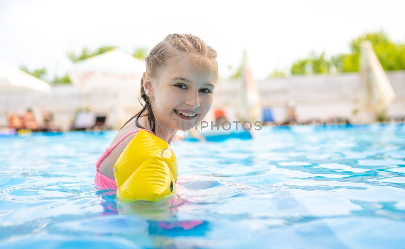 Little pretty girl kid in pool smiling and wearing colorful swimwear. Beautiful child enjoying summer holidays and swimming