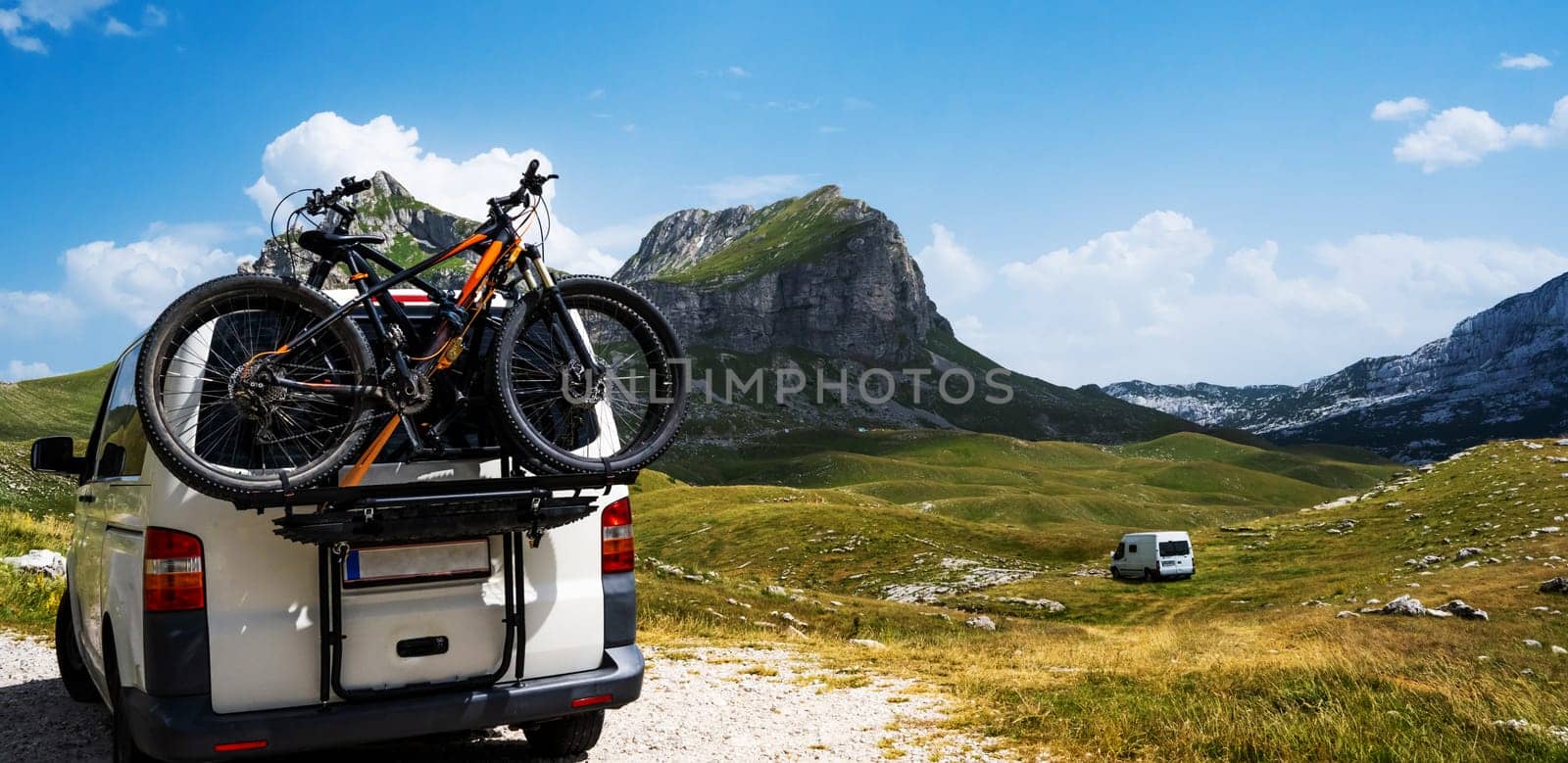 White car with bike in the mountains of National park Durmitor in Montenegro. Vehicle and beautiful nature landscape in sunny day