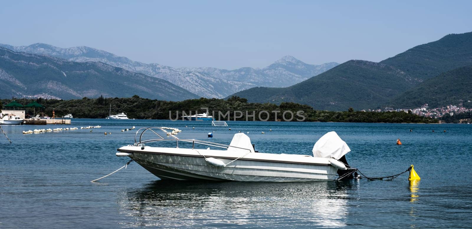 Boat in Adriatic sea, Montenegro with mountains on background. Sailboat transportaition in beautiful Mediterranean nature in sunny day
