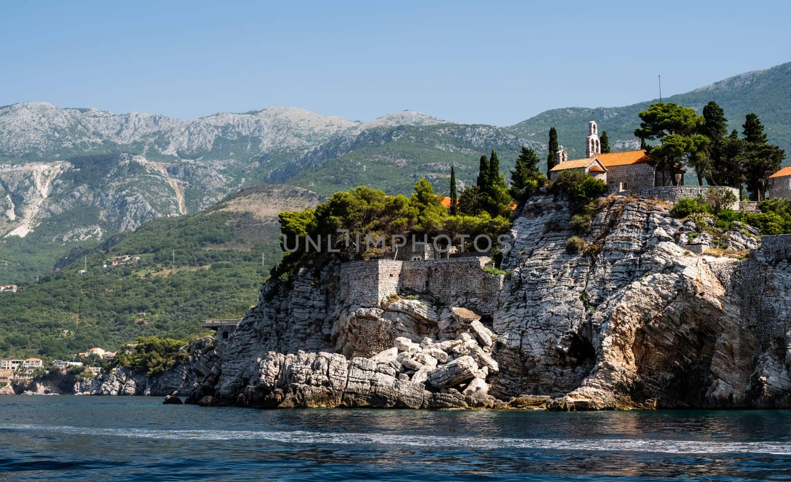 Scenic town on rocks in Montenegro, view from Adriatic sea. Beautiful Mediterranean architecture with nature in sunny day