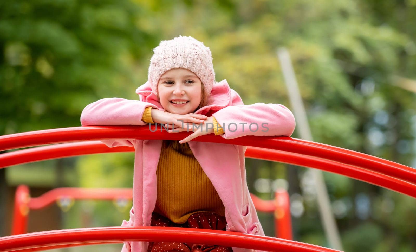 Pretty girl kid standing on playground at autumn day outdoors and daydreaming. Female child happy portrait