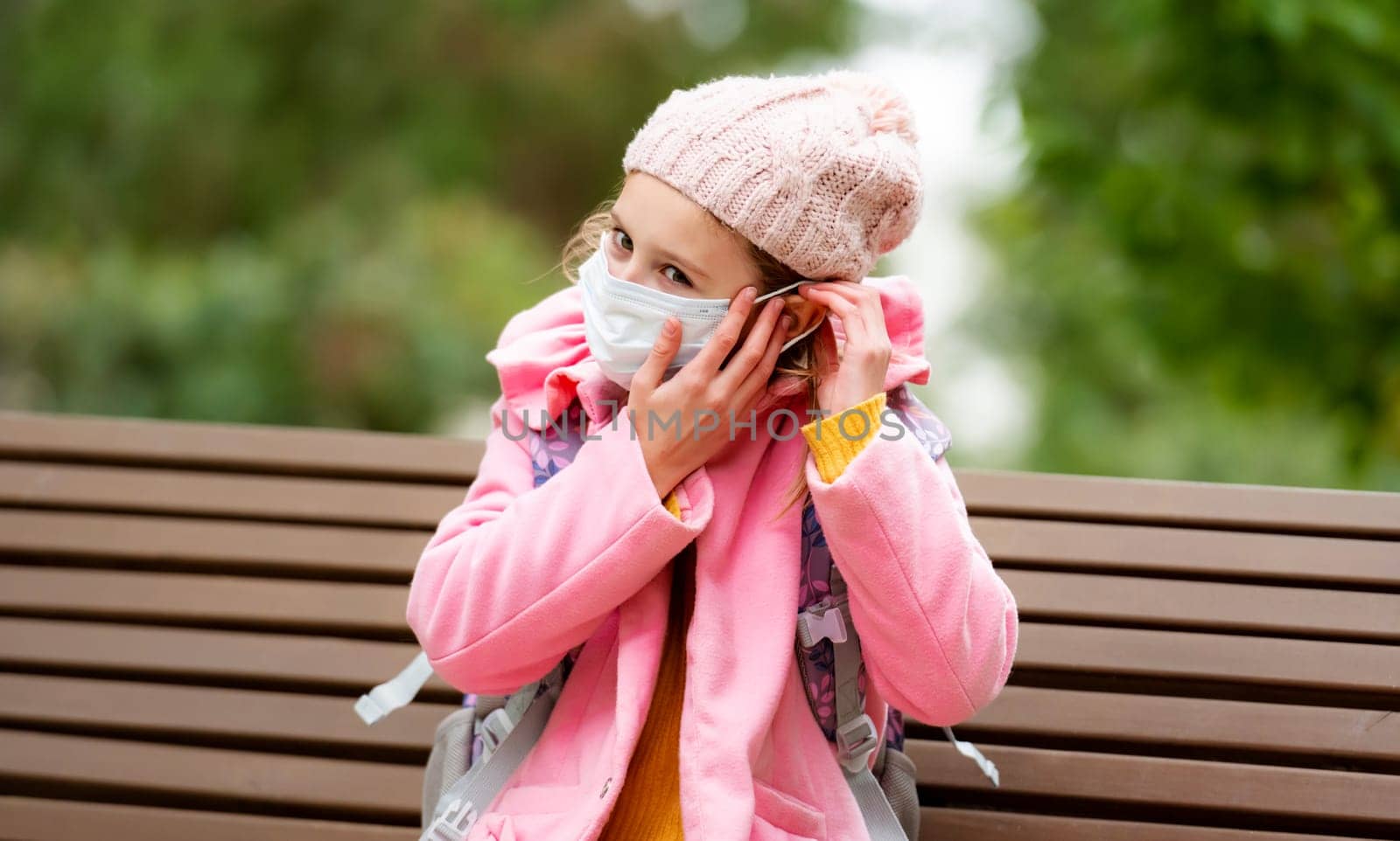 School girl kid wearing medicine mask at autumn park. Pretty female child cares about safety at pandemic coronavirus time