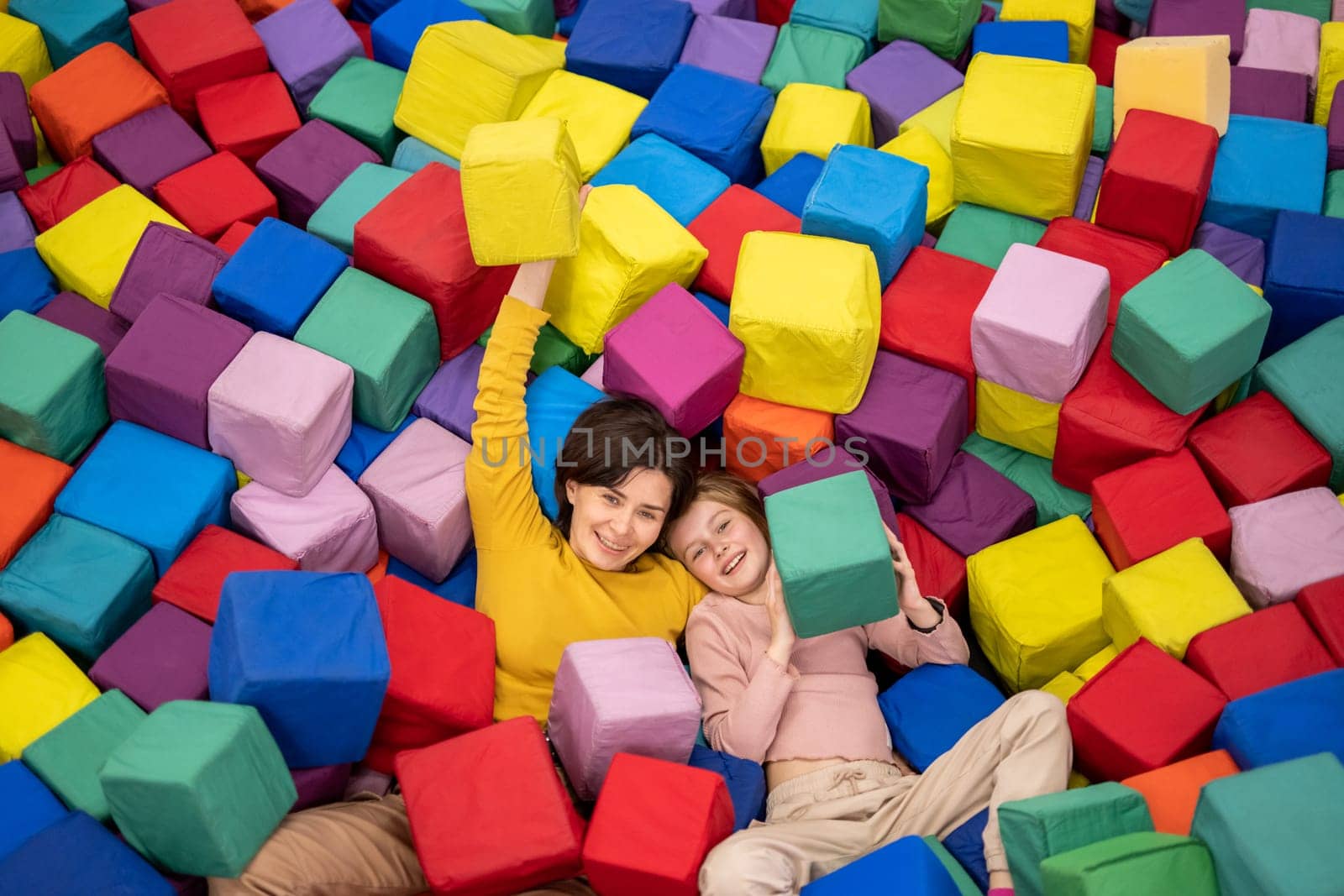 Pretty girl on trampoline holding colorful cube and smiling. Young woman happy during entertaiments at playground park
