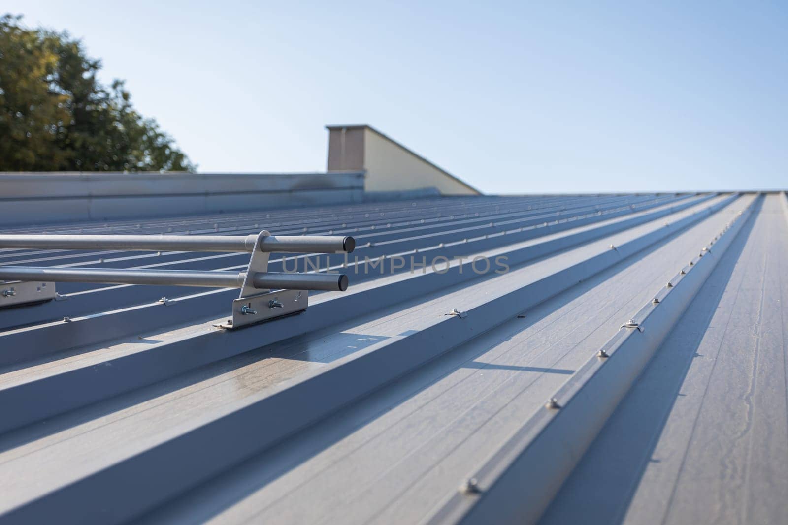 Systemic protection on the roof against sliding snow. Steep roof covered with trapezoidal sheets coated with graphite-colored paint.